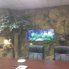 A Meeting Room. Behind, The Crystal Rock Panel Covers the Wall, with a cutout for a Large Fish Tank. 