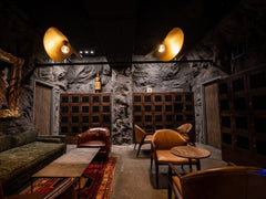 Large Basement Lounge, The Malawi Wall Panel Covering Back and Side Walls, with large lights hanging above on dark ceiling 