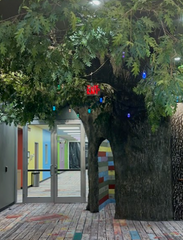 Large Faux Tree Entryway, With Pecan Panel mimicking bark. Above the Panel, Faux Leaves dangle in bunches